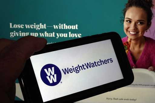 This image shows the logo of WeightWatchers on a mobile phone, and the company's website, in New Yo…