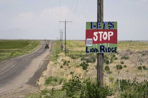 A tractor travels down Hunt Road in front of a "Let's Stop Lava Ridge" sign near the Minidoka Natio…