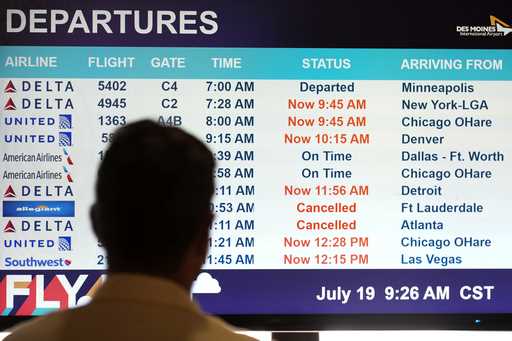 A passenger looks at a departures monitor at the Des Moines International Airport, Friday, July 19,…