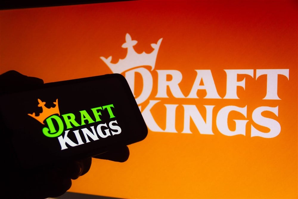 draftkings logo displayed on orange background and silhouette of mobile phone