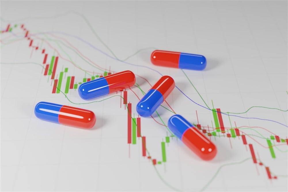 image of multicolored capsules on backdrop of declining stock graph