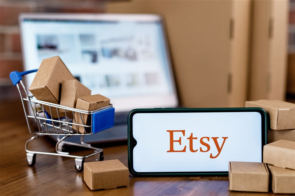 etsy logo displayed on smart phone next to toy cart with toy packages