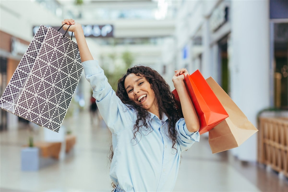 photo of smiling female shopper holding packages in the air