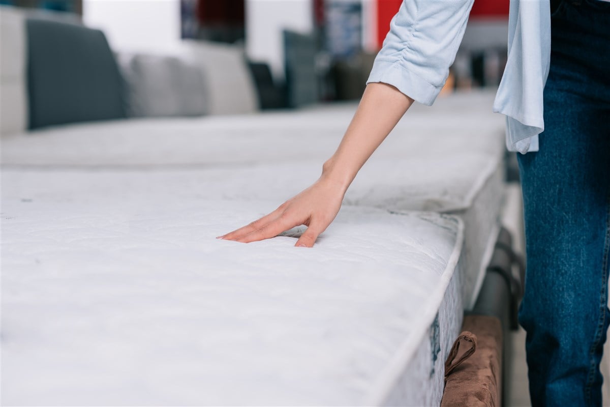 close-up image of female hand touching mattress