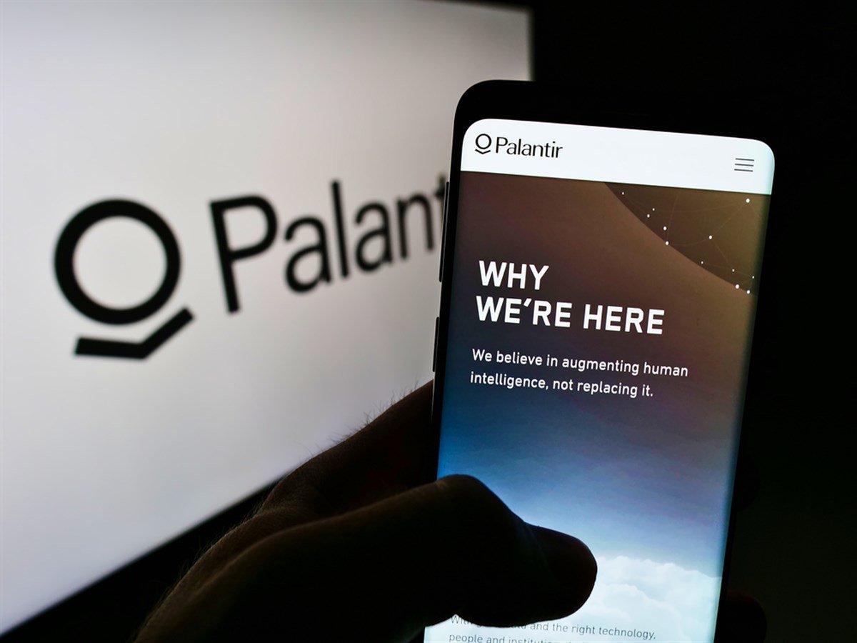 Person holding cellphone with web page of US software company Palantir Technologies Inc. on screen with logo.