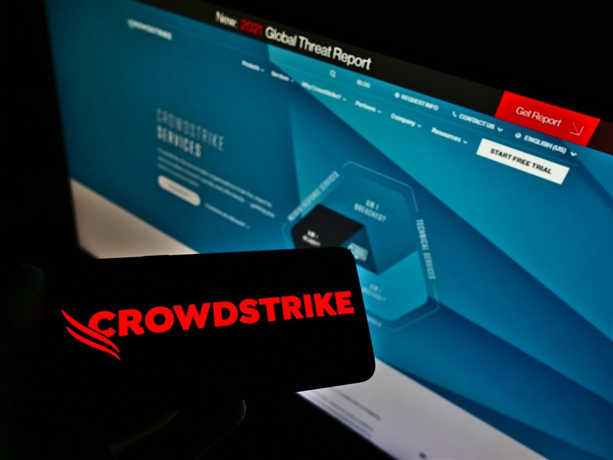 Person holding smartphone with logo of US software company CrowdStrike Holdings Inc. on screen in front of website