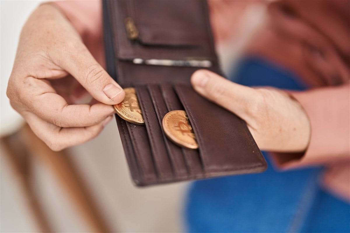 Photo of a person holding bitcoin of leather wallet