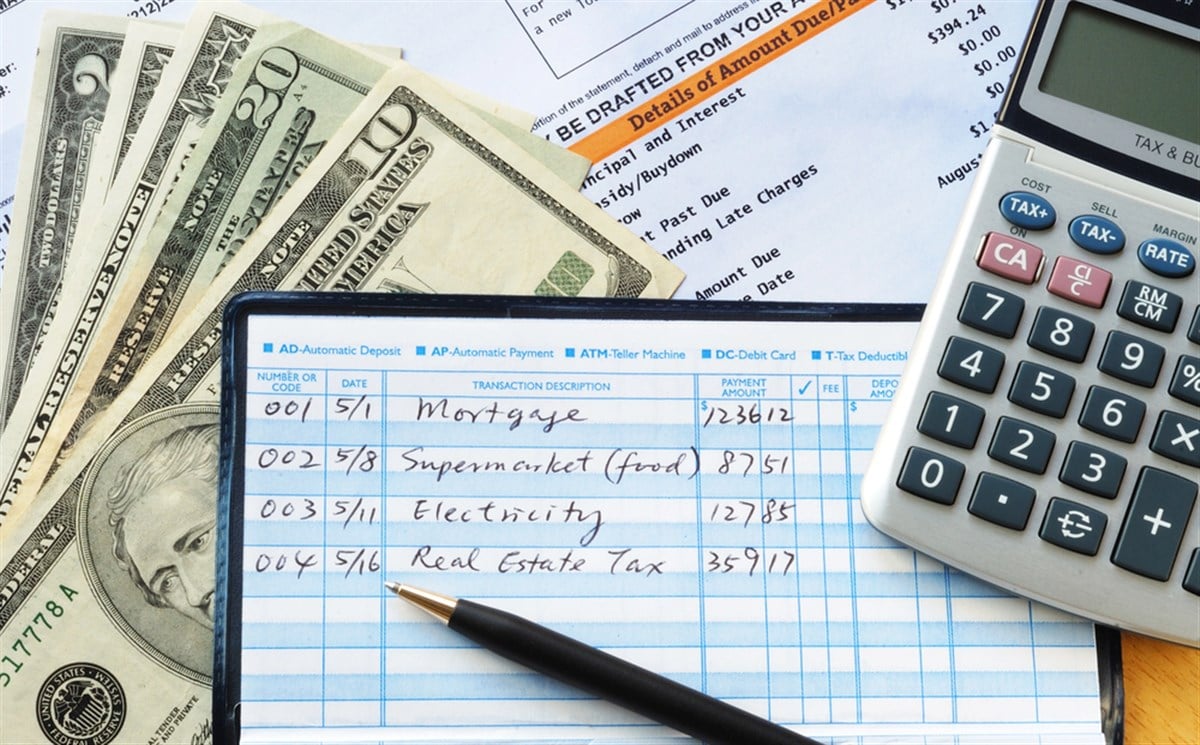 Photo of a check book, cash, and a calcuator.