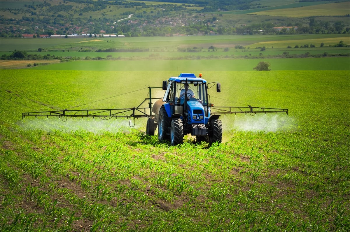 Farming tractor plowing and spraying on field  