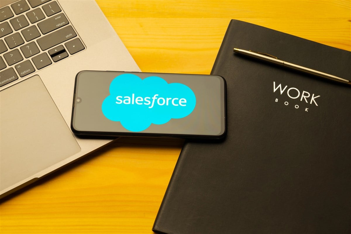 Salesforce.com displayed on a smartphone near modern laptop on wooden background