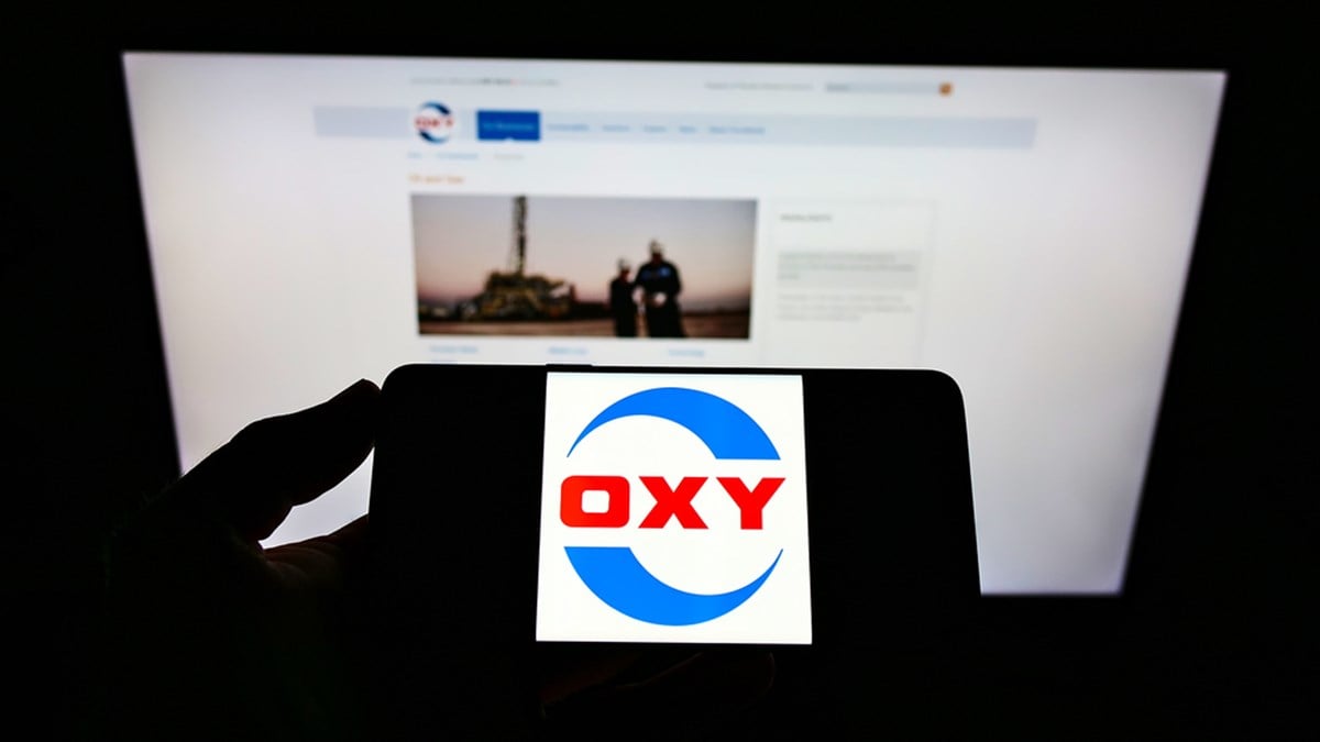 STUTTGART, GERMANY - Jun 07, 2021: Person holding mobile phone with logo of US company Occidental Petroleum Corporation (OXY) on screen in front of web page. Focus on phone display. - Stock Editorial Photography