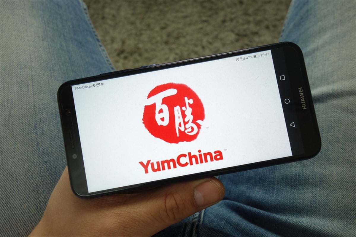 KONSKIE, POLAND - April 13, 2019: Man holding smartphone with Yum China restaurant company logo — Stock Editorial Photography