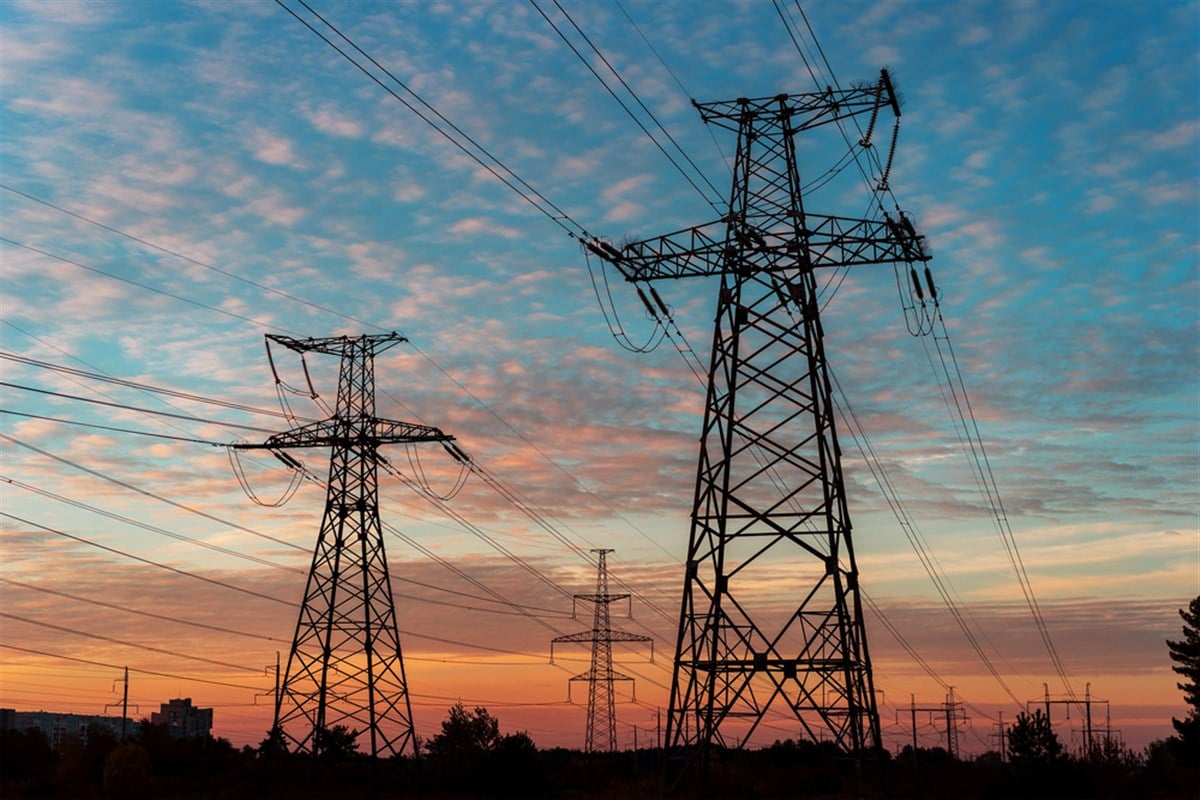 Electricity pylons and lines at dusk at sunset. - stock image