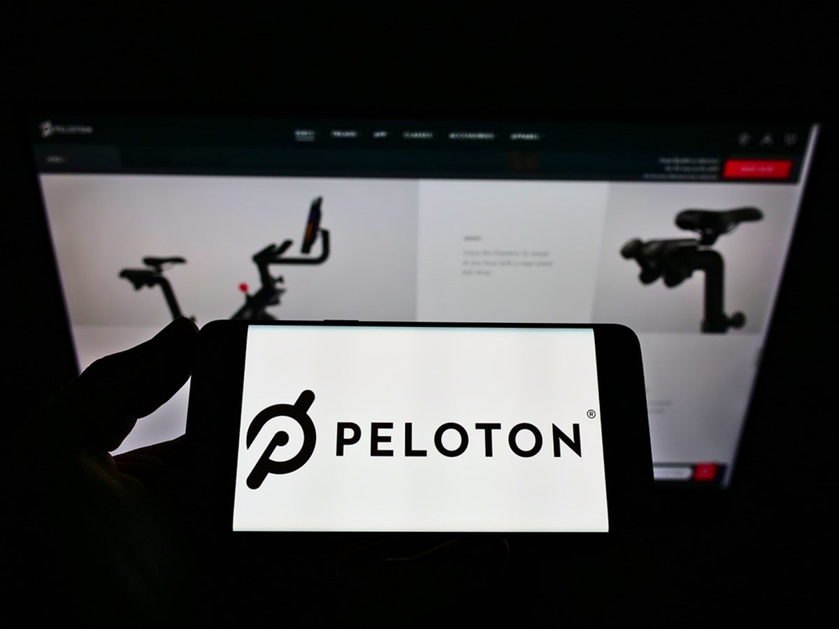 STUTTGART, GERMANY - Jun 08, 2021: Person holding cellphone with logo of US company Peloton Interactive Inc. on screen in front of business webpage. Focus on phone display. - Stock Editorial Photography