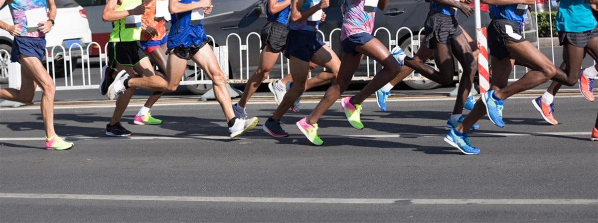 Marathon runners legs running on city road - stock image