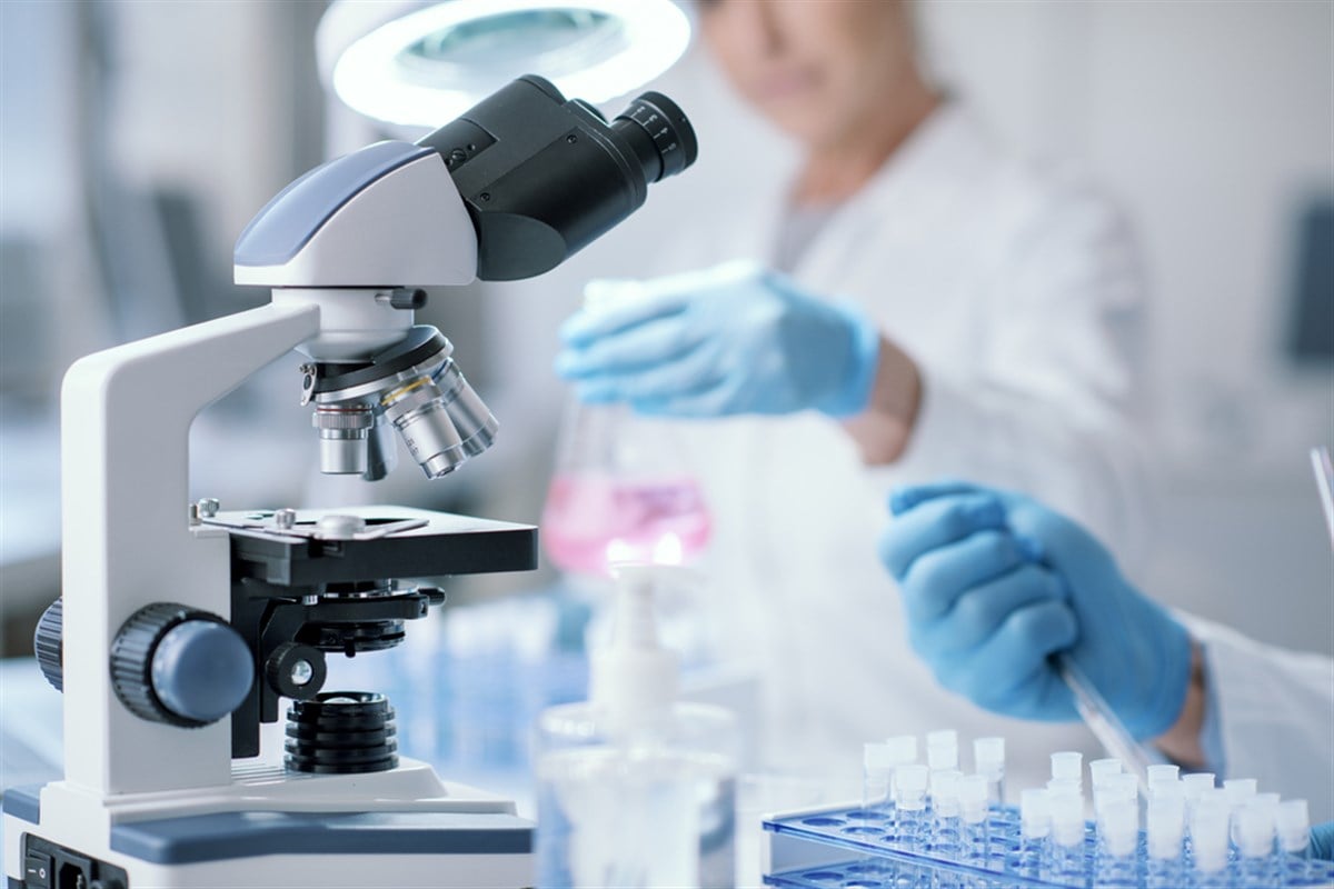 Scientists working together in the medical laboratory, microscope in the foreground