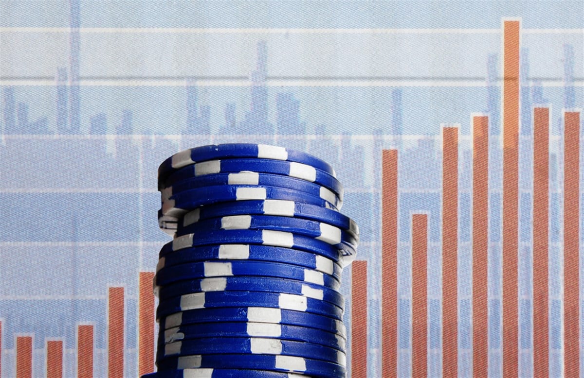 Photo of blue poker chips against a stock chart background