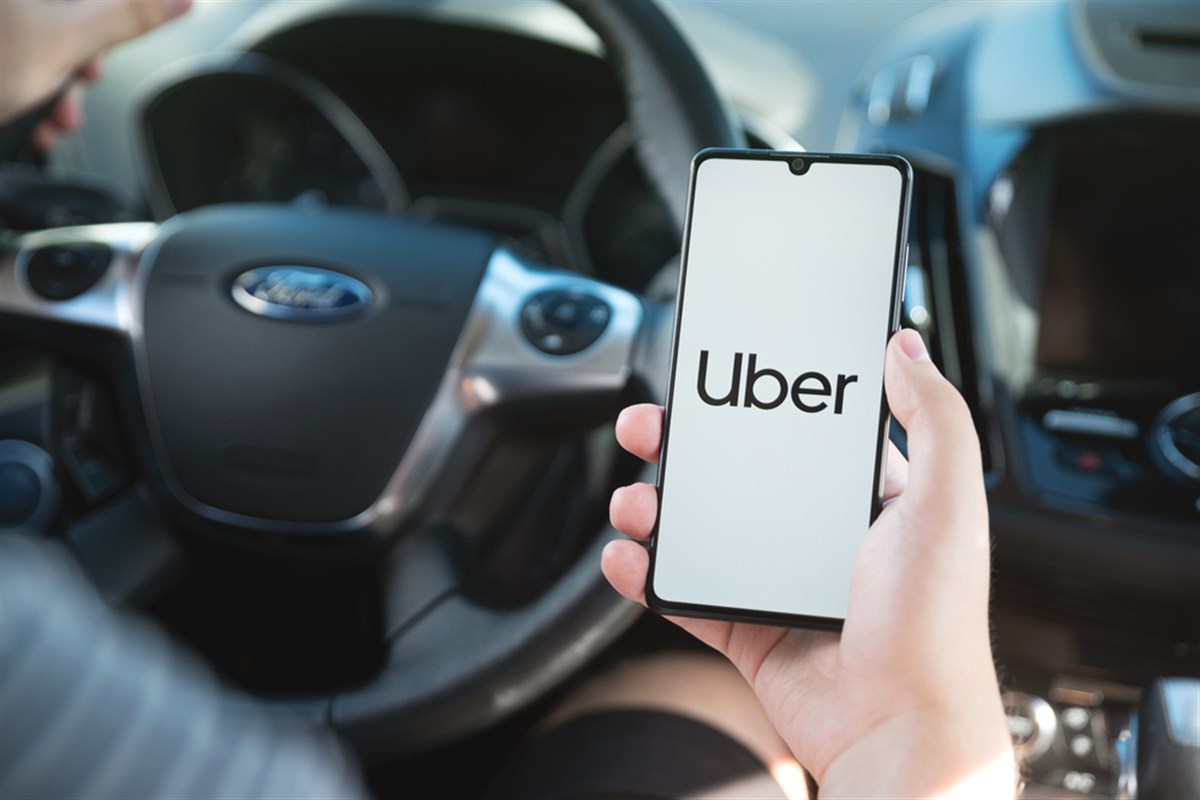 Wroclaw, Poland - AUG 25, 2020: Uber driver holding smartphone in car. Uber is sharing-economy service for ubran transport.