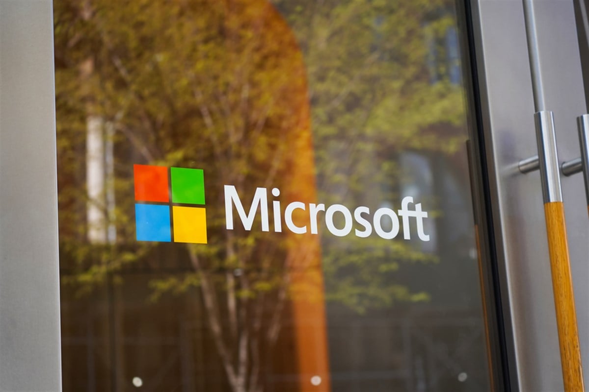 New York, NY - April 9, 2023: Microsoft logo on glass door on SoHo Manhattan shop with green tree reflection. — Stock Editorial Photography