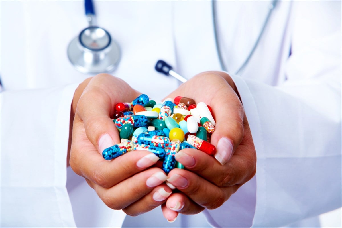 Photo of a woman's hands cupping a variety of multi-colored pills