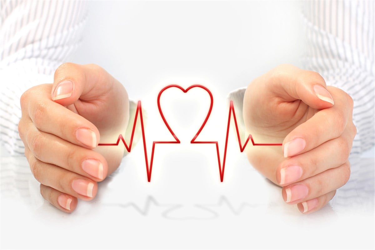 Photo of two hands cupping a red heart monitor line shaped like a heart