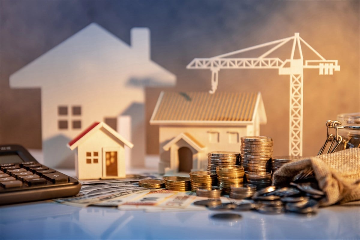 Real estate or property development. Construction business investment concept. Home mortgage loan rate. Coin stack on international banknotes with calculator, house and crane models on the table. — Photo