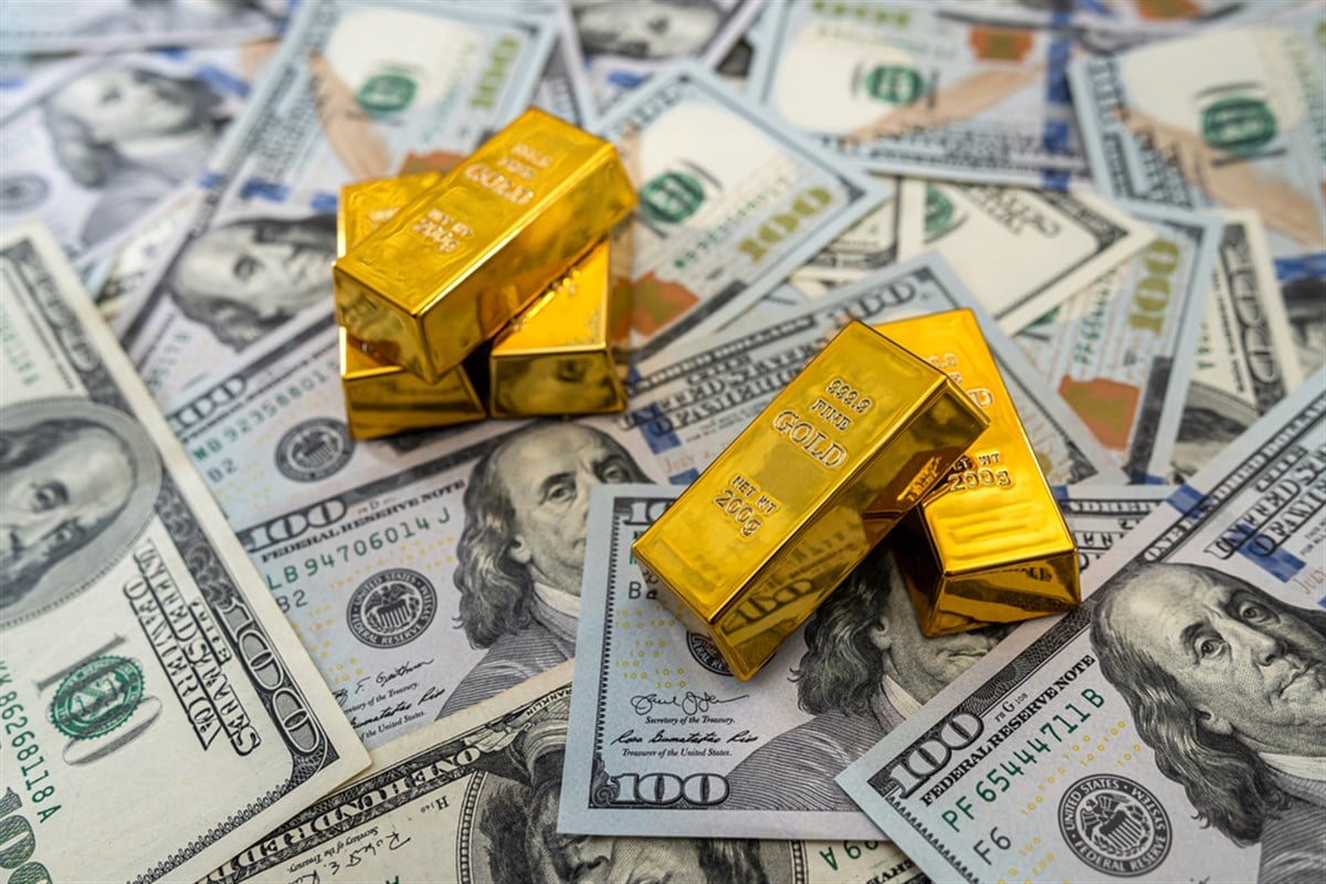 Gold bullion on pile us dollar bills as background. finance and saving concept — Photo