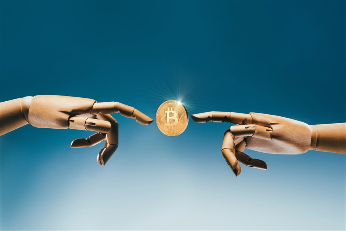 photo of two robot hands pointing at a Bitcoin