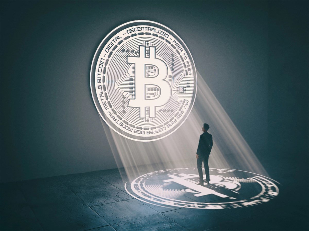 Photo of a Bitcoin illuminating a businessman in a suit.