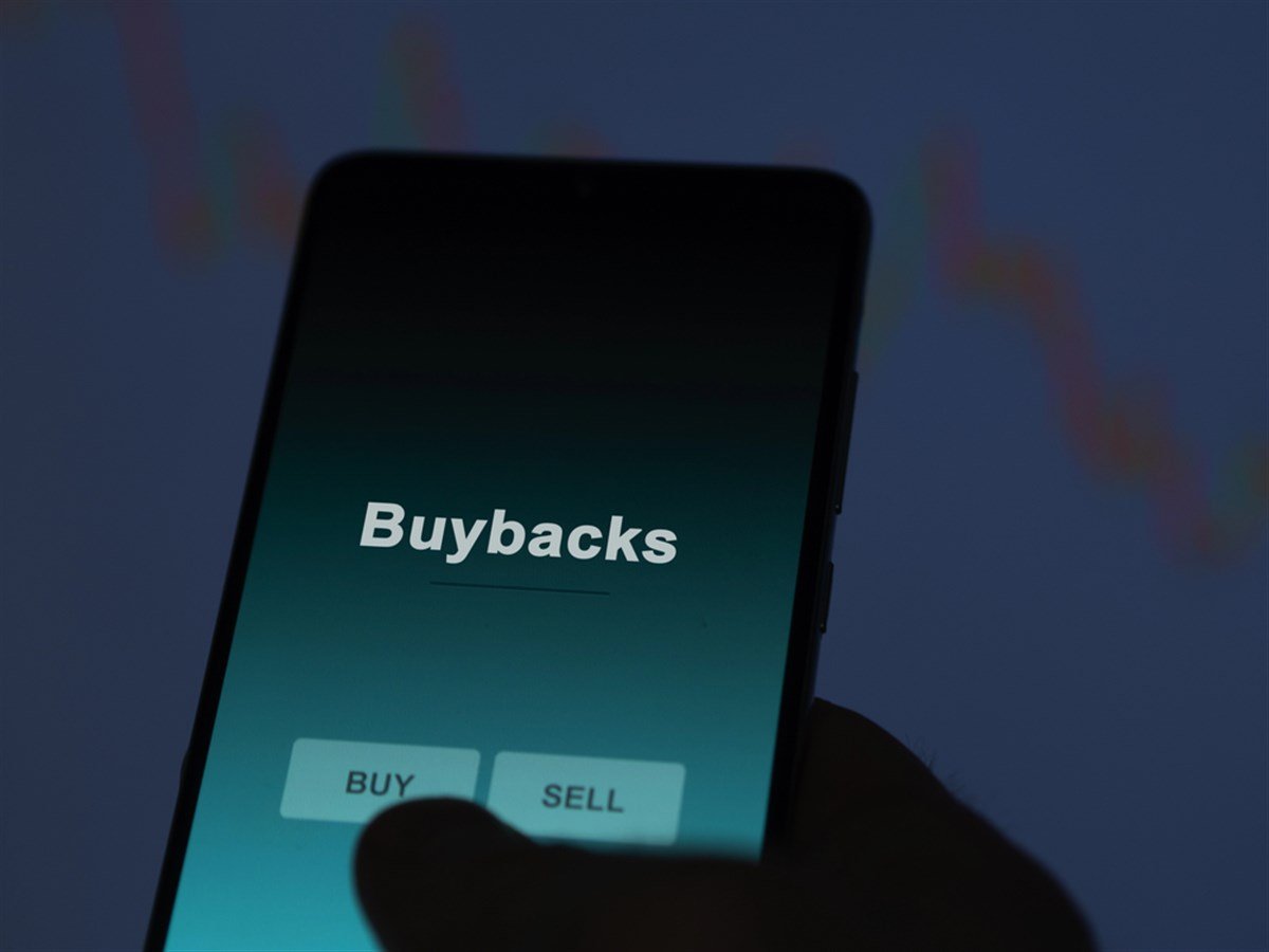 An investor analyzing the buybacks etf fund on a screen. A phone shows the prices of Buybacks — Photo