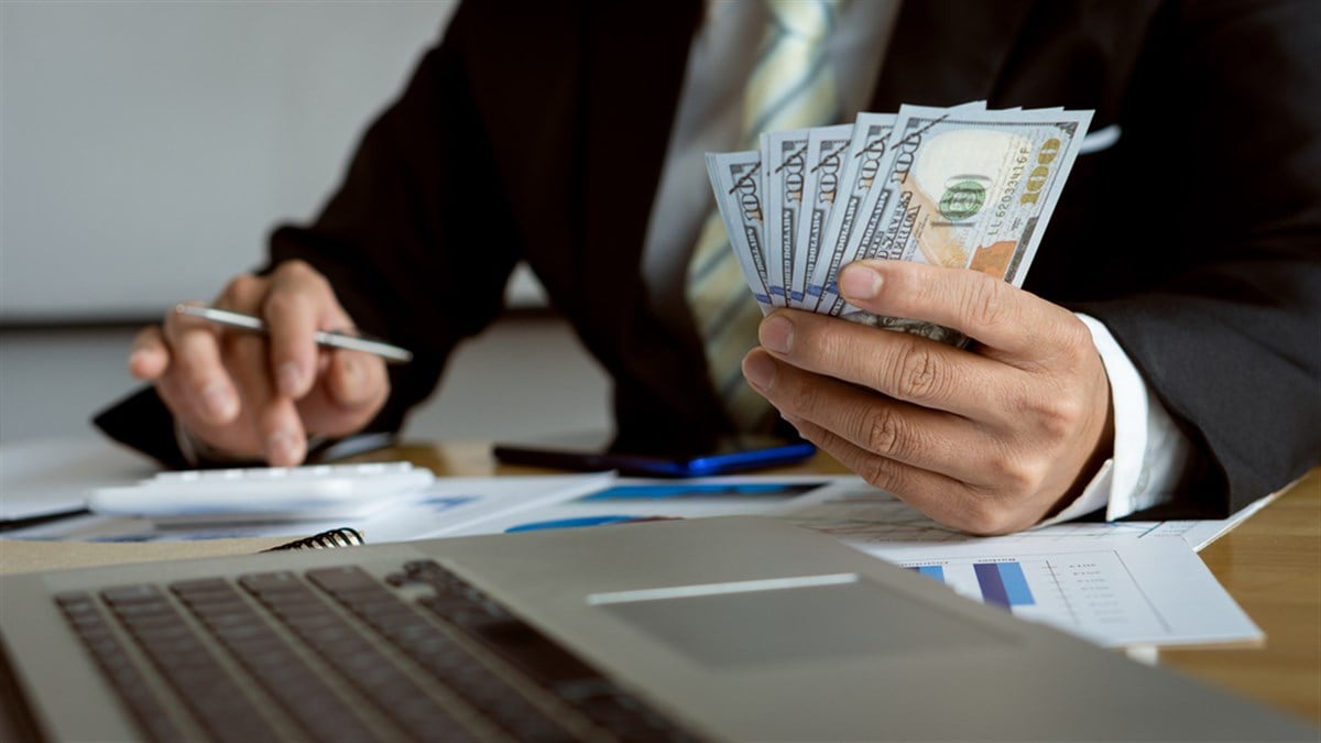 businessman counting banknotes on wooden table with calculator and laptop Concept of counting money. Salary. Paying employees in a company office. — Photo