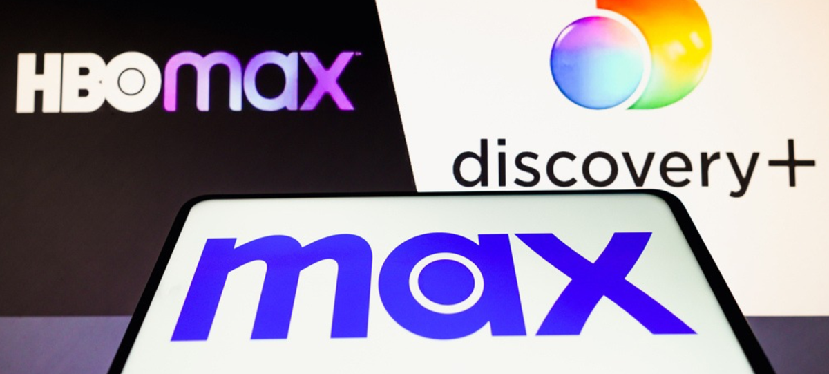 Photo of "Max" on a smartphone screen, with HBO Max and Discovery+ logos behind it.