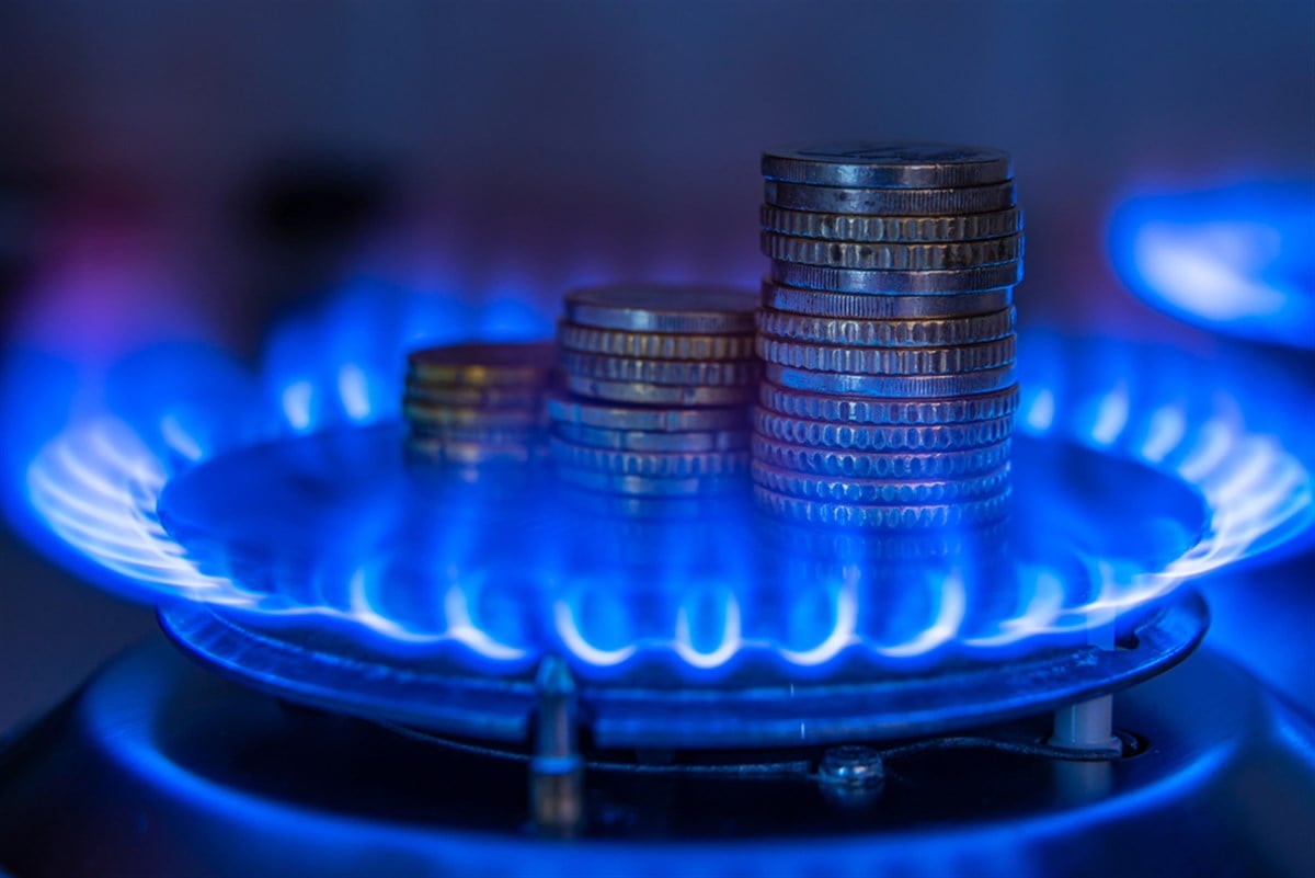 Gas stove lit, with stacks of coins above it. Increase in gas costs and tariffs. — Photo