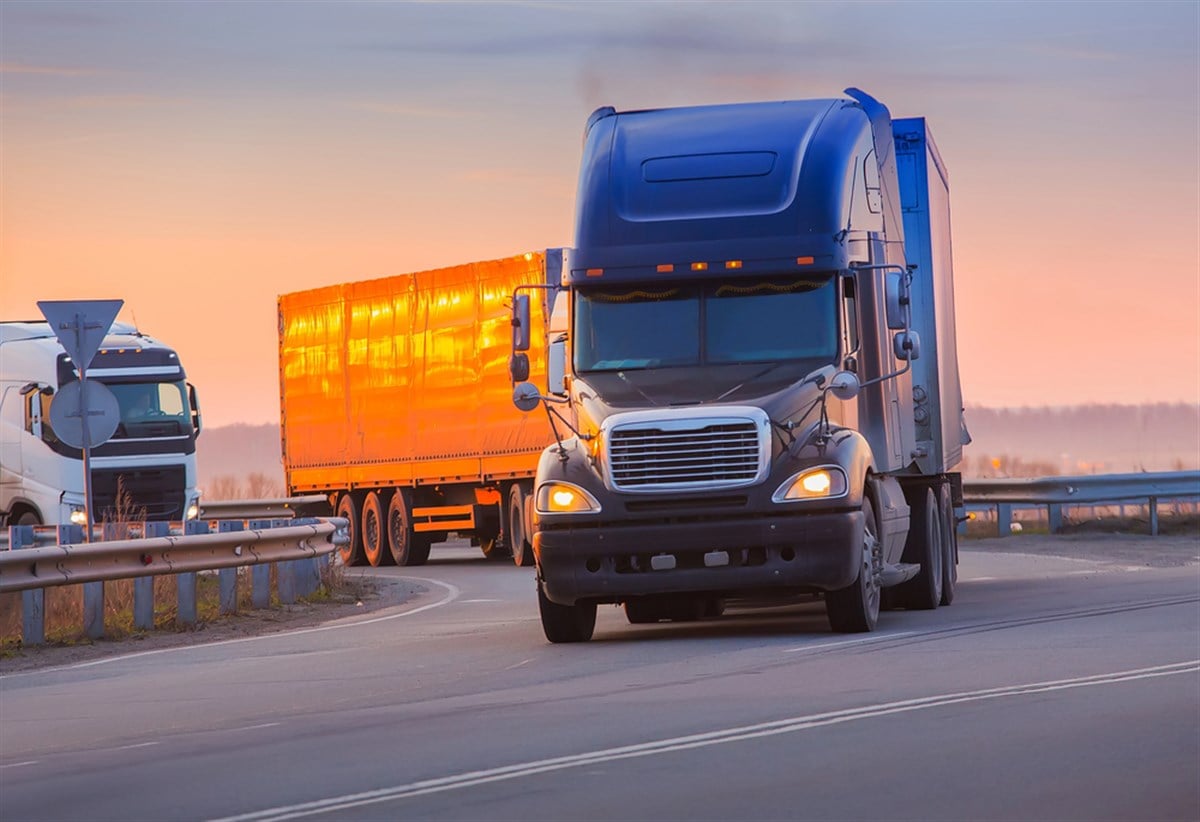 Trucks goes on highway on sunset - stock image