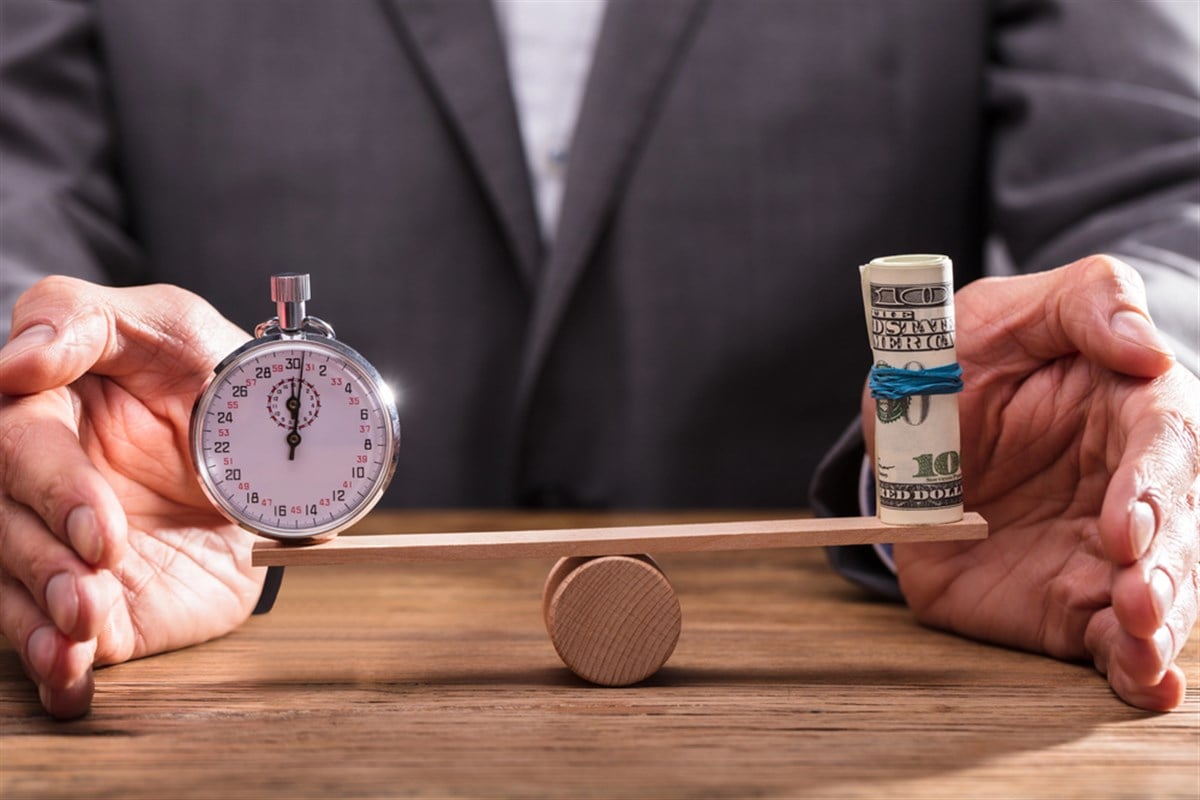 Photo of two hands balancing time and money