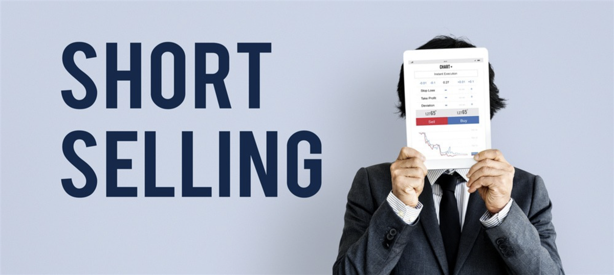 Photo of a businessman holding a financial graph in front of his face, standing next to the words Short Selling