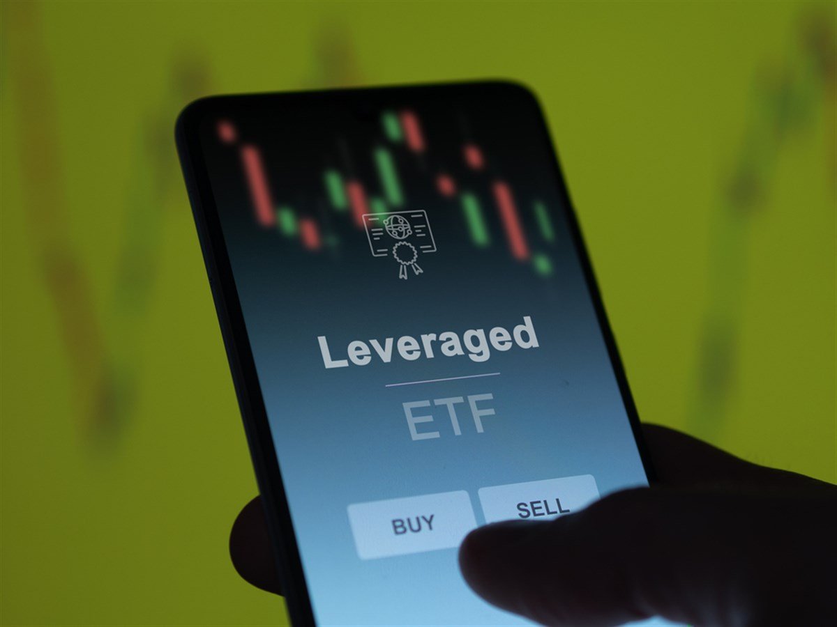 An investor analyzing the leveraged etf fund on a screen. A phone shows the prices of Leveraged - stock image