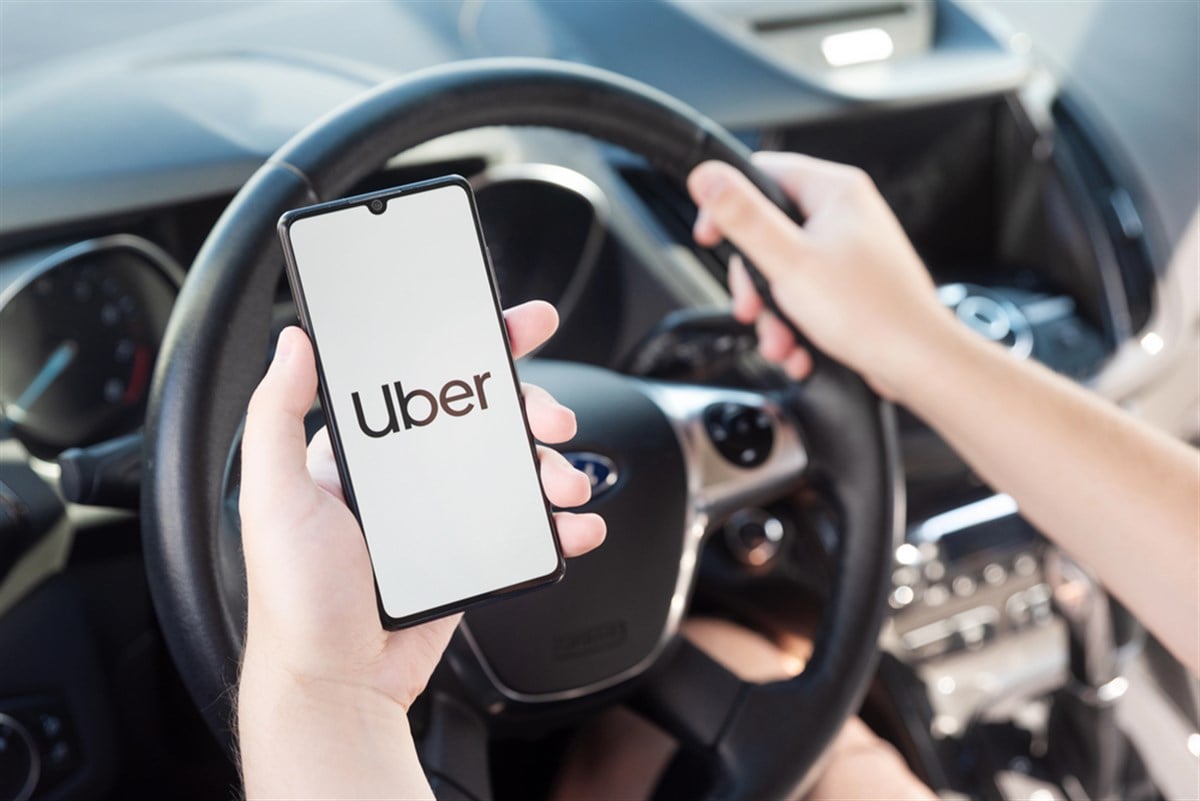 Wroclaw, Poland - AUG 25, 2020: Uber driver holding smartphone in car. Uber is sharing-economy service for ubran transport. - Stock Editorial Photography