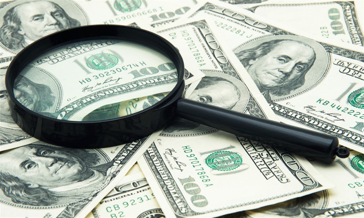 Magnifying glass and money - business background