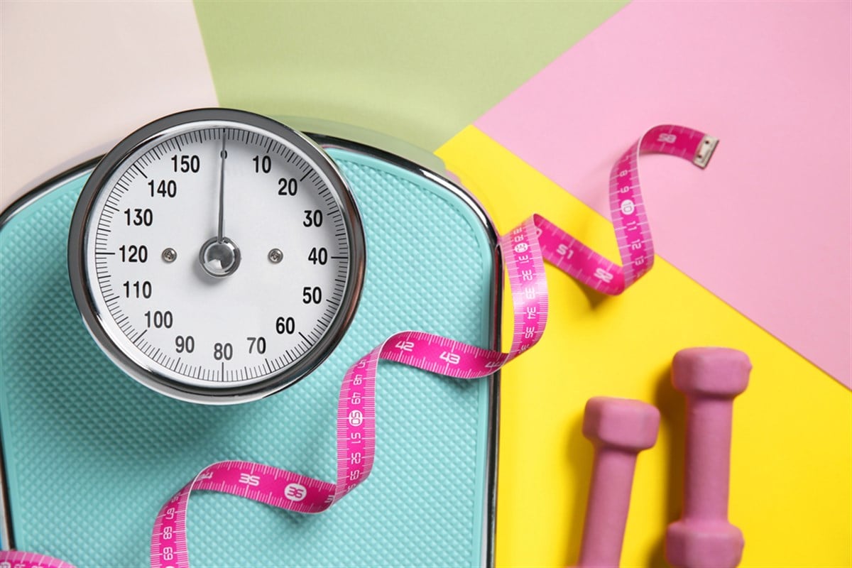 Scale, dumbbells and measuring tape on color background, flat lay — Photo