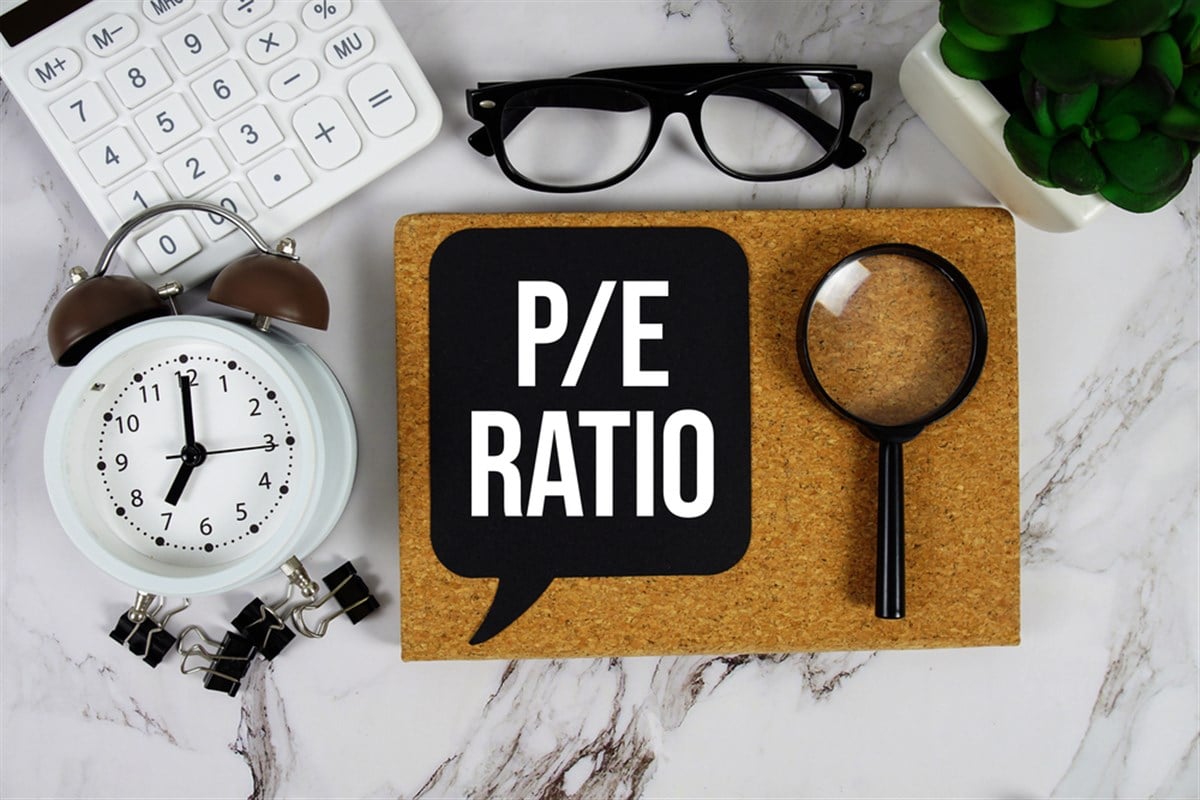 P/E Ratio acronyms Price-To-Earnings text on speech bubble with alarm clock, calculator and magnifying glass on marble background — Photo