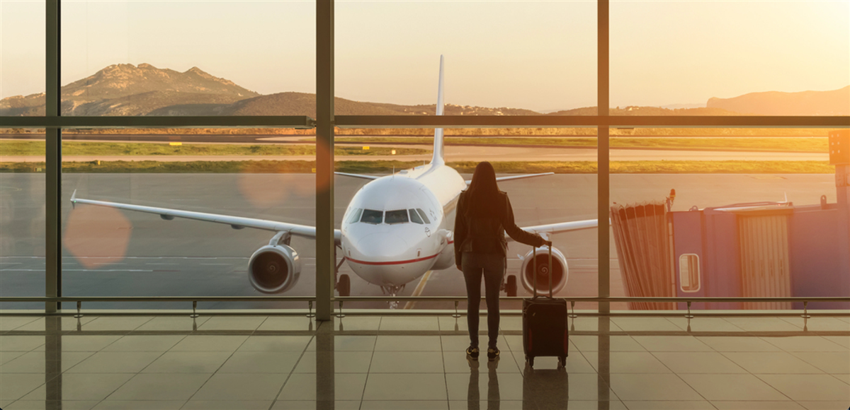 Young woman with suitcase in the departure hall at airport. Travel concept. — Photo