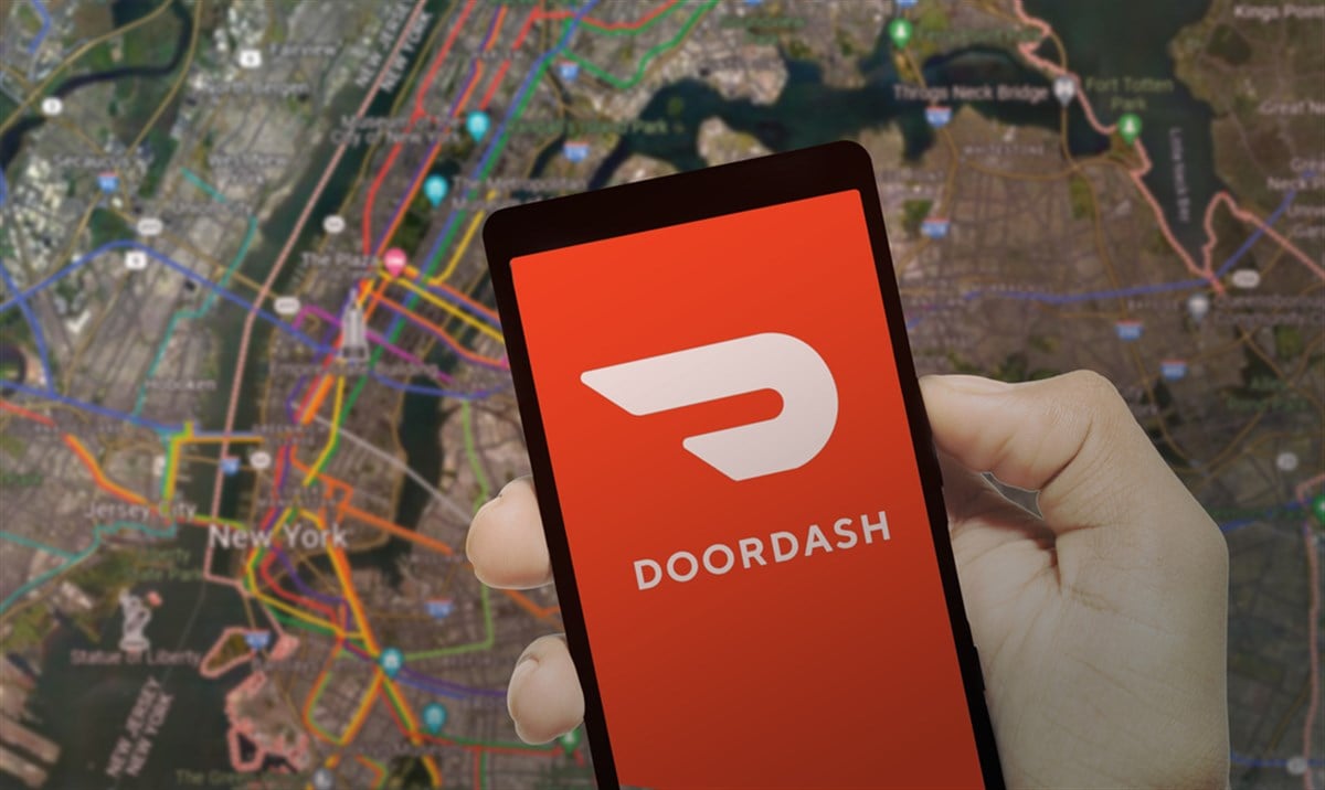 DoorDash logo with smartphone with food delivery service, background map. — Stock Editorial Photography