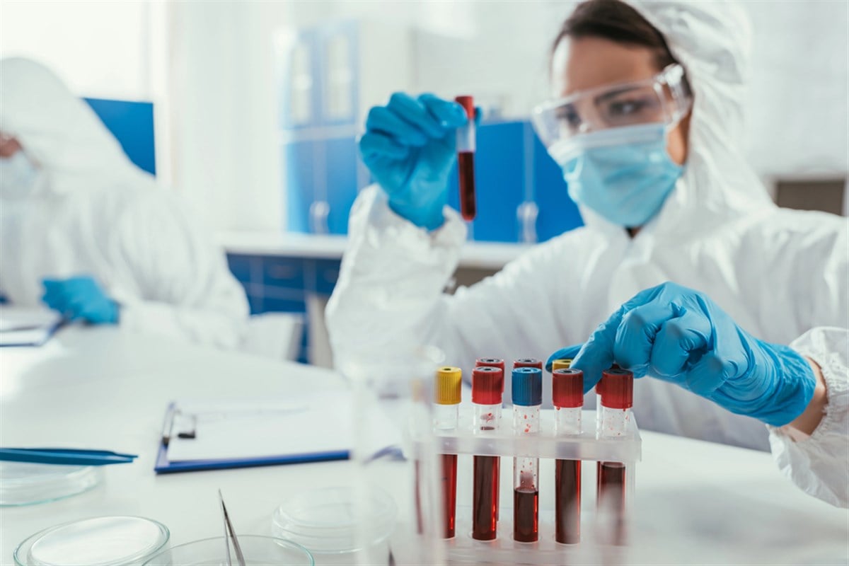 Biochemist holding test tube with blood sample near colleague in laboratory — Photo