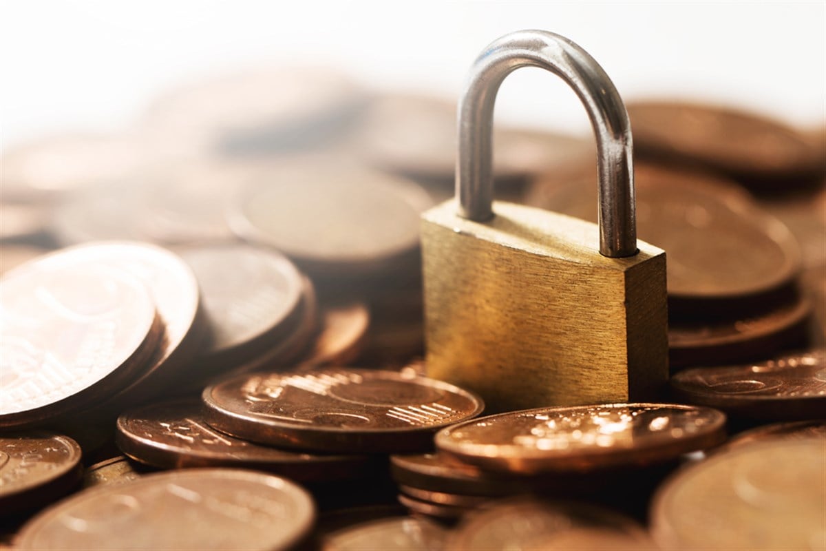 Small brass lock on a pile of shiny copper euro coins.