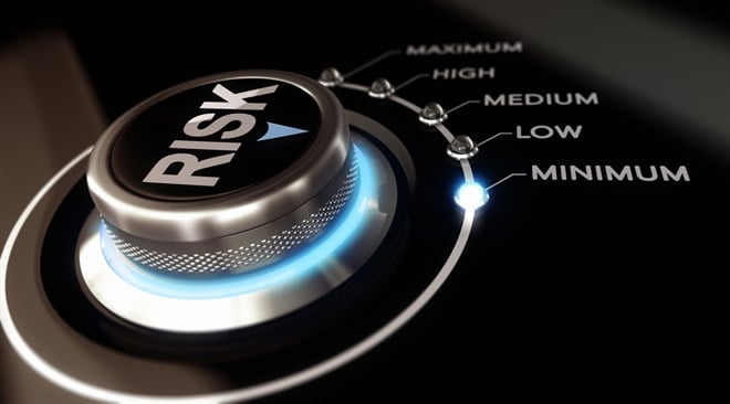 Photo of a switch button with the word Risk on it positioned on the word minimum, black background and blue light. Risk Tolerance vs Risk Capacity: Key Differences & How to Measure.