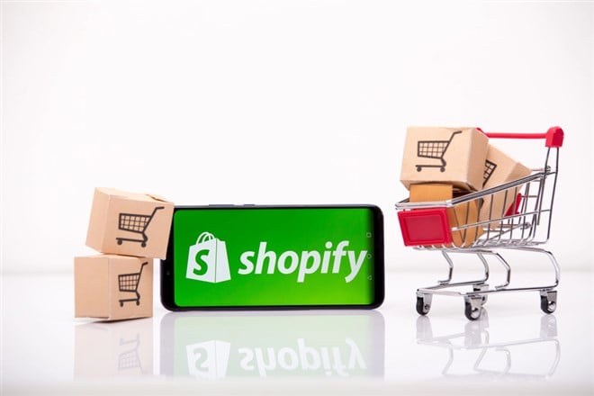 shopify logo on smartphone next to shopping cart