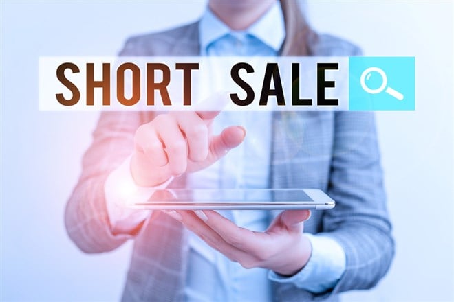 Photo of a business man holding a computer with the words Short Sale in an englarged search bar. Understanding Short Interest: What It Really Means for Investors.