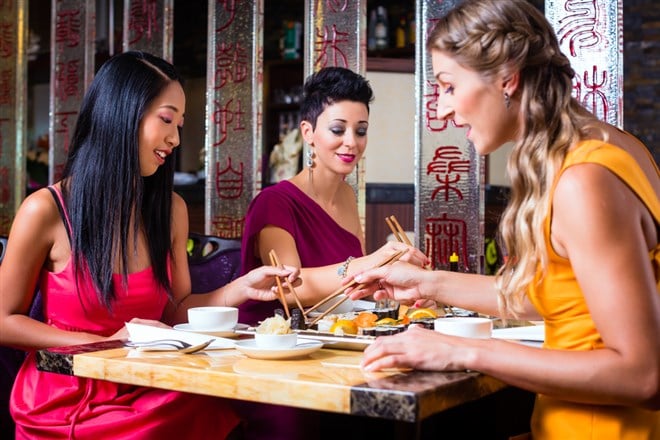 Young people eating sushi in Asian restaurant