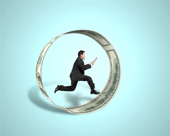 Photo of a businessman running inside a circle made of money symbolic of the wheel options trading strategy. 